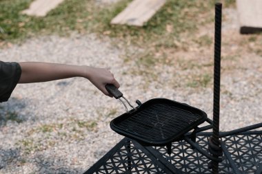 Bir kadın kamp sırasında ızgara yapmak için sıcak tava kullanıyor..