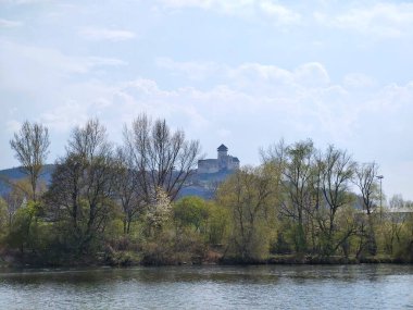 Dağların tepesindeki kalenin manzarası, göl ve ağaçlar.