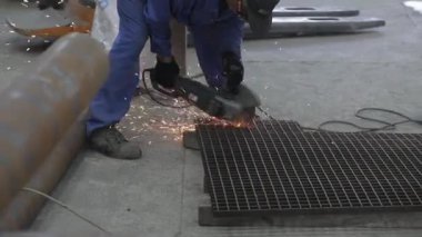 Sakallı tamirci benzin istasyonunda metal kesiyor.