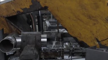 Metal atölyesindeki öğütme makinesinin yardımıyla çelik borunun bir kısmına kaynak yapılmış dikiş.