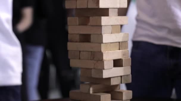 Freunde sitzen in der Küche und spielen ein Jenga-Brettspiel. Sie reden und amüsieren sich und trinken Getränke. Das Konzept der Entspannung und Unterhaltung. — Stockvideo