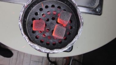 Arap kafesindeki shisha kasesindeki kömürler. Geleneksel nargile kömürü görüntüsü. Sigara içmek ve doğal ışıklandırmada boş vakit geçirmek için.