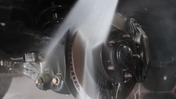 Miespuolinen työntekijä pesee auton. Puhdistus auton avulla korkeapaine vesi. — kuvapankkivideo