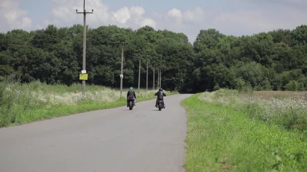 Motociclista motociclista monta uma moto. Passeios em uma estrada rural Aventuras em uma bicicleta de gato na natureza. — Vídeo de Stock