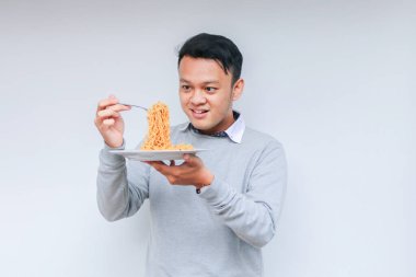 Genç Asyalı mutlu adamın portresi erişteden hoşlanıyor. Öğle yemeği konsepti..