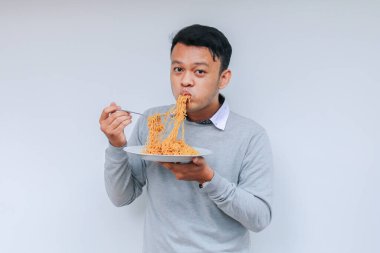 Genç Asyalı adam eriştenin tadını çıkarıyor. Öğle yemeği konsepti..