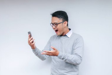 Genç Asyalı adam, gri arka planda gördüğü şey karşısında şok olmuş ve mutlu..