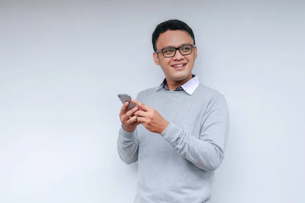 聪明的亚洲年轻人在工作室背景下使用智能手机时 会很开心 也很开心 — 图库照片