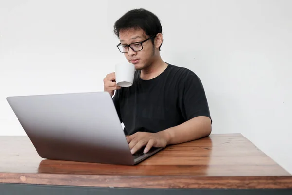 Ung Asiatisk Mann Smiler Nyter Jobbe Hjemme Med Laptop Kaffe – stockfoto