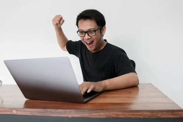 Lykkelig Asiatisk Mann Med Bærbar Som Løfter Armen Feire Suksess – stockfoto