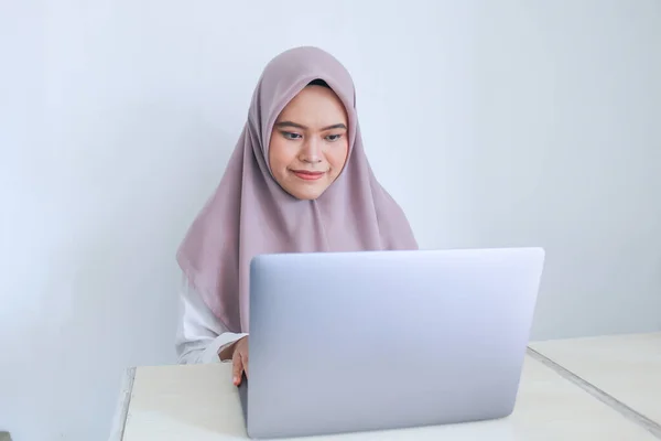 スカーフを被った若いアジア系イスラム教徒の女性は ラップトップで見たことに笑顔と幸せがあります 灰色の背景のインドネシア人女性 — ストック写真