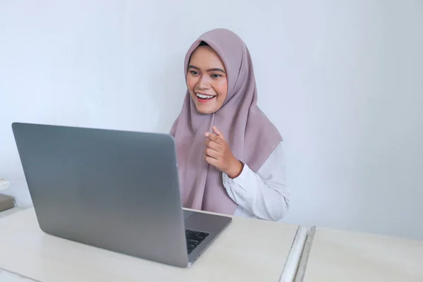 头戴头巾的年轻的亚洲伊斯兰妇女对她在笔记本电脑上看到的东西充满了微笑和快乐 灰色背景的印度尼西亚妇女 — 图库照片