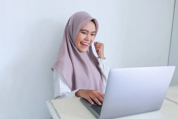スカーフを被った若いアジア系イスラム教徒の女性は スマートフォンで見たことを喜んで祝うことができます 灰色の背景のインドネシア人女性 — ストック写真