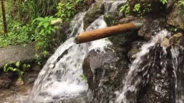 Endonezya 'nın Bali köyü kırsal kesiminde geleneksel kırsal bambu ve kayadan güzel şelale damlası.
