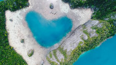 Raja Ampat, Papua, Endonezya 'daki kayalık tropikal adanın içinde kalbinde turkuaz su bulunan Aşk Gölü Karwapop' un havadan görünüşü.