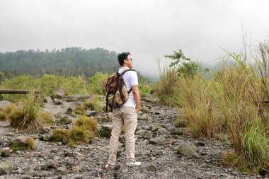 Genç Asyalı sırt çantalı adam mutlu ve dağlarda gezmekten hoşlanıyor..