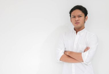 Beyaz gömlek giyen genç Asyalı adam ciddi ve keskin görünümlü bir şekilde el ele tutuşuyor. Gri arka planda başarılı Endonezyalı adam.