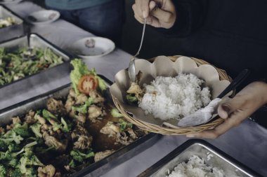 İnsan eli, restoranda öğle yemeği sırasında Yakiniku tavuğunu çelik tavadan ahşap kağıt tabağa koyar.