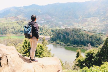 Genç Asyalı sırt çantalı adam mutlu ve dağlarda gezmekten hoşlanıyor..