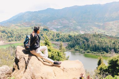 Genç Asyalı sırt çantalı adam mutlu ve dağlarda gezmekten hoşlanıyor..