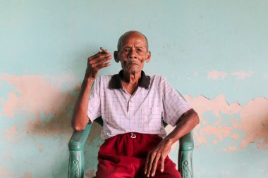 Elinde sigarayla Asyalı Cava ihtiyarının yakın portresi.