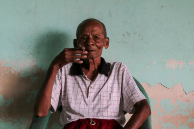 Elinde sigarayla Asyalı Cava ihtiyarının yakın portresi.