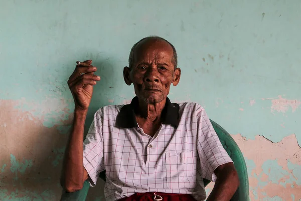 Close up portrait of Asian Javanese old man with a cigarette in his hand