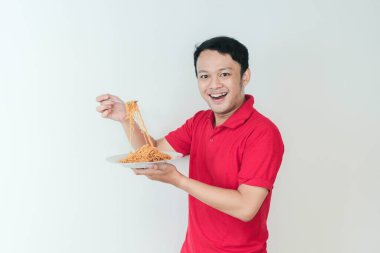 Genç Asyalı mutlu adamın portresi erişteden hoşlanıyor. Öğle yemeği konsepti..