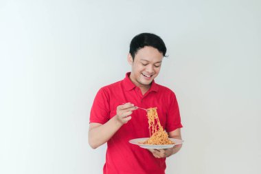 Genç Asyalı mutlu adamın portresi erişteden hoşlanıyor. Öğle yemeği konsepti..