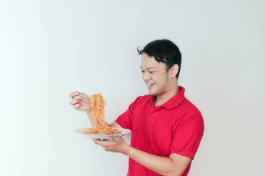 Genç Asyalı mutlu adamın portresi erişteden hoşlanıyor. Öğle yemeği konsepti..