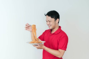 Genç Asyalı mutlu adamın portresi erişteden hoşlanıyor. Öğle yemeği konsepti..