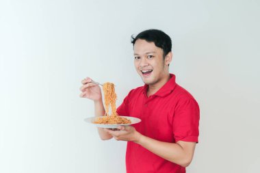 Genç Asyalı mutlu adamın portresi erişteden hoşlanıyor. Öğle yemeği konsepti..