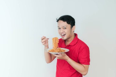 Genç Asyalı mutlu adamın portresi erişteden hoşlanıyor. Öğle yemeği konsepti..