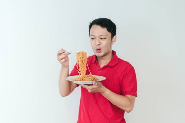 Genç Asyalı mutlu adamın portresi erişteden hoşlanıyor. Öğle yemeği konsepti..