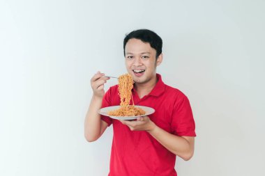 Genç Asyalı mutlu adamın portresi erişteden hoşlanıyor. Öğle yemeği konsepti..
