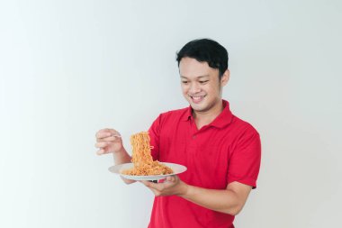 Genç Asyalı mutlu adamın portresi erişteden hoşlanıyor. Öğle yemeği konsepti..