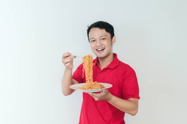 Genç Asyalı mutlu adamın portresi erişteden hoşlanıyor. Öğle yemeği konsepti..