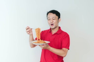 Genç Asyalı mutlu adamın portresi erişteden hoşlanıyor. Öğle yemeği konsepti..