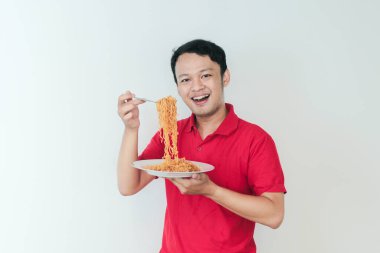 Genç Asyalı mutlu adamın portresi erişteden hoşlanıyor. Öğle yemeği konsepti..