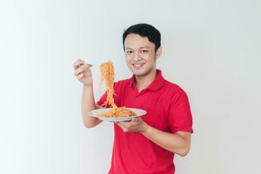 Genç Asyalı mutlu adamın portresi erişteden hoşlanıyor. Öğle yemeği konsepti..