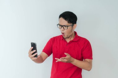 Genç Asyalı adamın yüzü, gri arka planda akıllı telefonda gördüklerini şok etti..