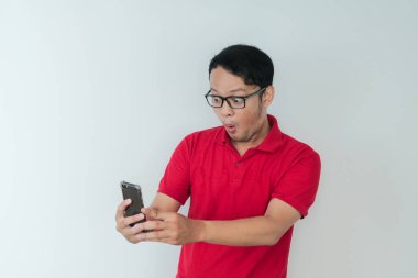 Genç Asyalı adamın yüzü, gri arka planda akıllı telefonda gördüklerini şok etti..