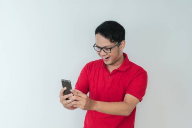 Genç Asyalı adam, gri arka planda gördüğü şey karşısında şok olmuş ve mutlu..