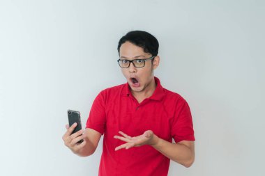 Genç Asyalı adamın yüzü, gri arka planda akıllı telefonda gördüklerini şok etti..