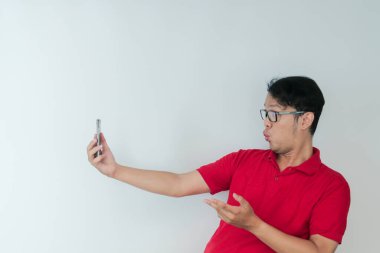 Genç Asyalı adamın yüzü, gri arka planda akıllı telefonda gördüklerini şok etti..