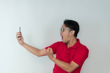 Genç Asyalı adamın yüzü, gri arka planda akıllı telefonda gördüklerini şok etti..