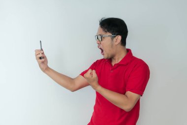 Genç Asyalı adamın yüzü, gri arka planda akıllı telefonda gördüklerini şok etti..