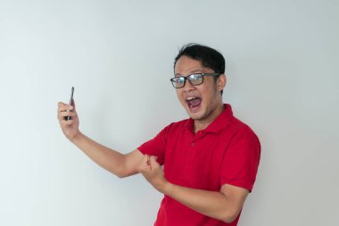 Genç Asyalı adam, gri arka planda gördüğü şey karşısında şok olmuş ve mutlu..