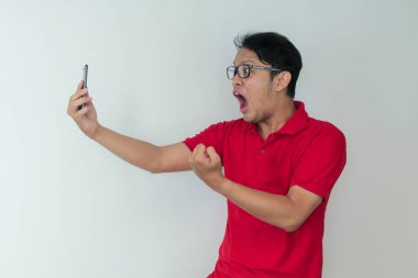 Genç Asyalı adamın yüzü, gri arka planda akıllı telefonda gördüklerini şok etti..