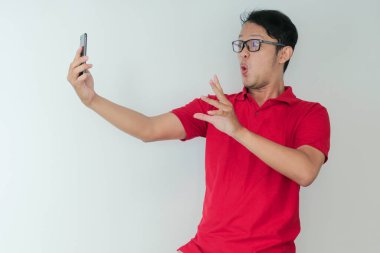 Genç Asyalı adamın yüzü, gri arka planda akıllı telefonda gördüklerini şok etti..